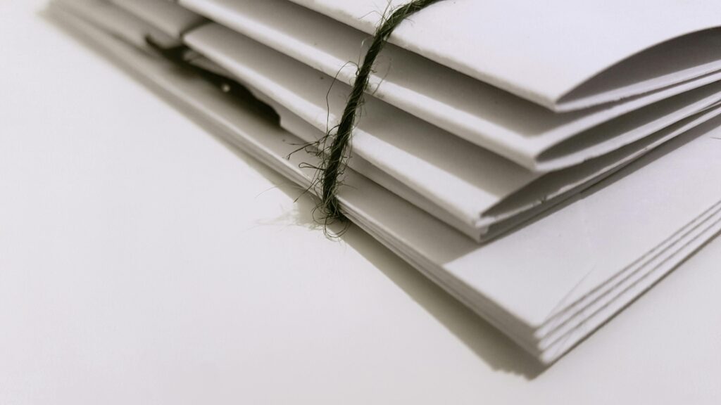 pexels-photo-1764956-1764956 Pile of white envelopes tied with a green string, showcasing a minimalist design.
