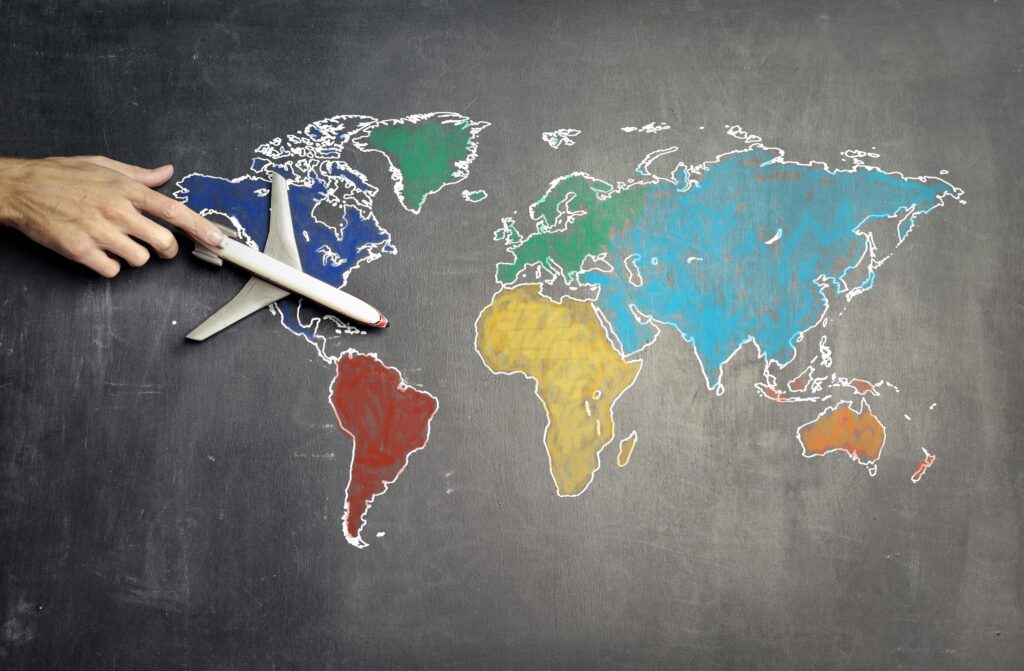 pexels-photo-3769138-3769138 Top view of crop anonymous person holding toy airplane on colorful world map drawn on chalkboard