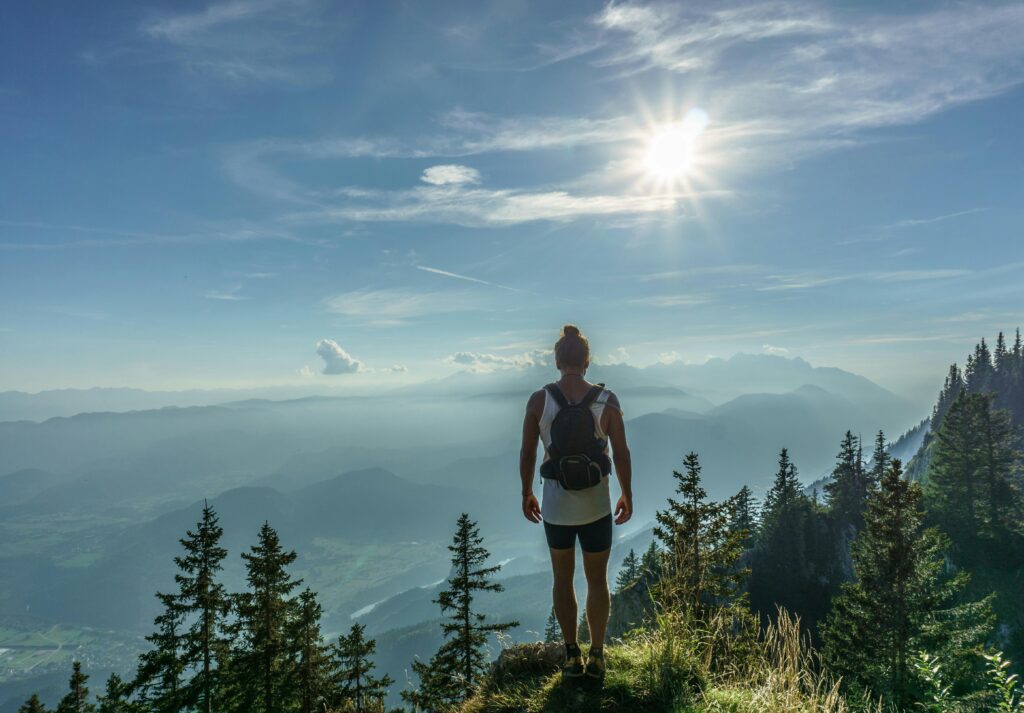 pexels-photo-547116-547116 A lone hiker stands on a mountain top, overlooking a breathtaking landscape in Slovenia under the bright sun.